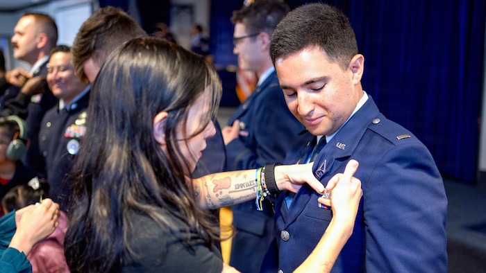 A U.S. Space Force Guardian officer has a lapel pin pinned onto their uniform by a loved one during an Officer Training Course graduation ceremony at Peterson Space Force Base, Colorado, June 26, 2026.