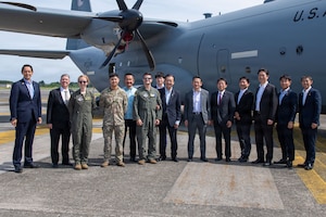 A group of people pose in front of a plane.