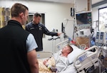 SAN DIEGO (Aug. 21, 2025) — Cmdr. Daniel Hammer, left, maxillofacial surgeon and director of the Maxillofacial Restoration Program at Naval Medical Center San Diego, and Lt. Cmdr. Stephen Moreno, oral maxillofacial surgery residency program assistant director, check on U.S. Army Spc. Grant Dickerson in the intensive care unit two days after the performed his jaw-in-a-day surgery. Dickerson had the surgery to remove a tumor that had destroyed two-thirds of his lower jaw and rebuild the damaged portion. (DoW photo by Regena Kowitz)