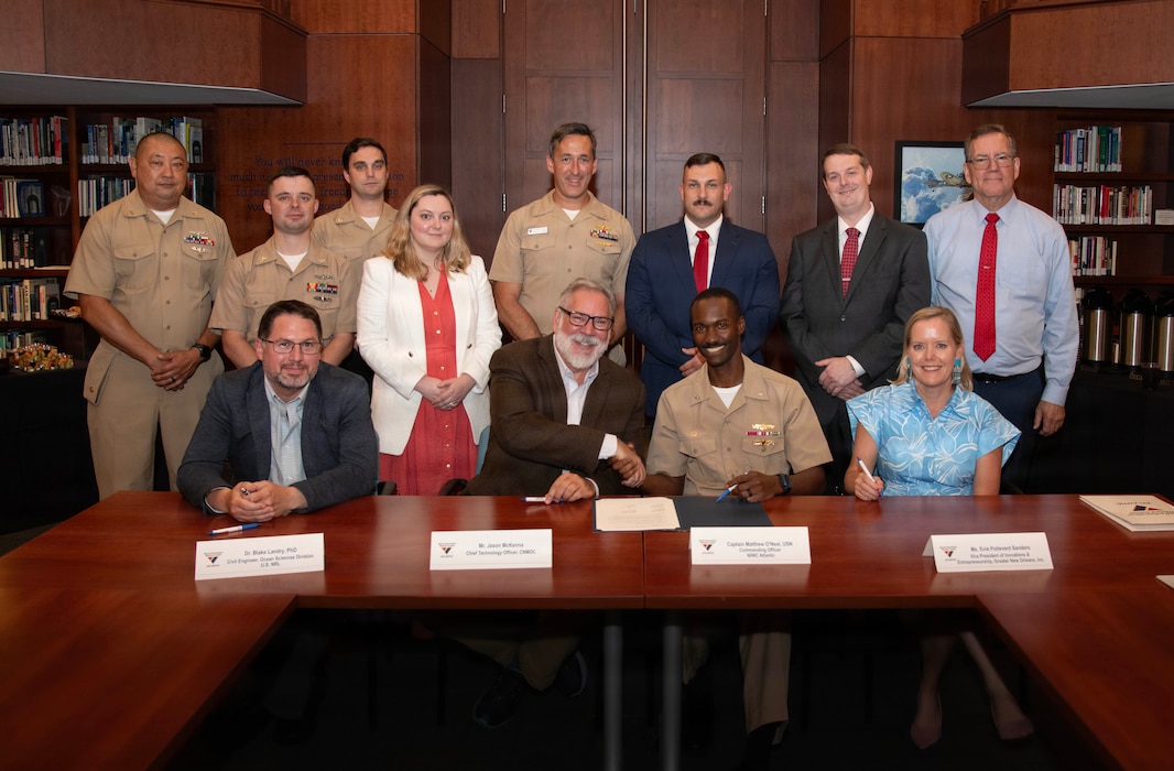Four military and defense leaders sit at a long table inside the National WWII Museum, signing a strategic alliance memorandum of agreement for the Gulf Coast Defense Catalyst.
