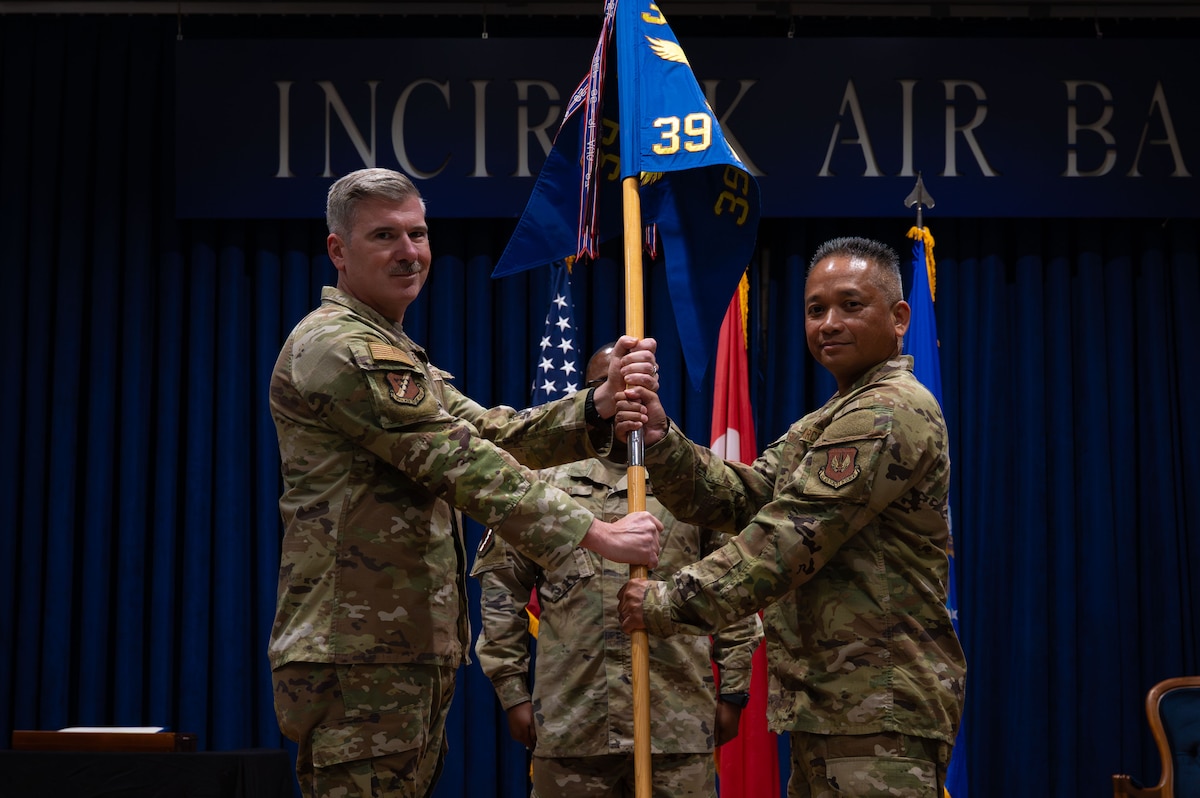 A man gives another man a guidon staff.