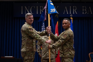 A man gives another man a guidon staff.
