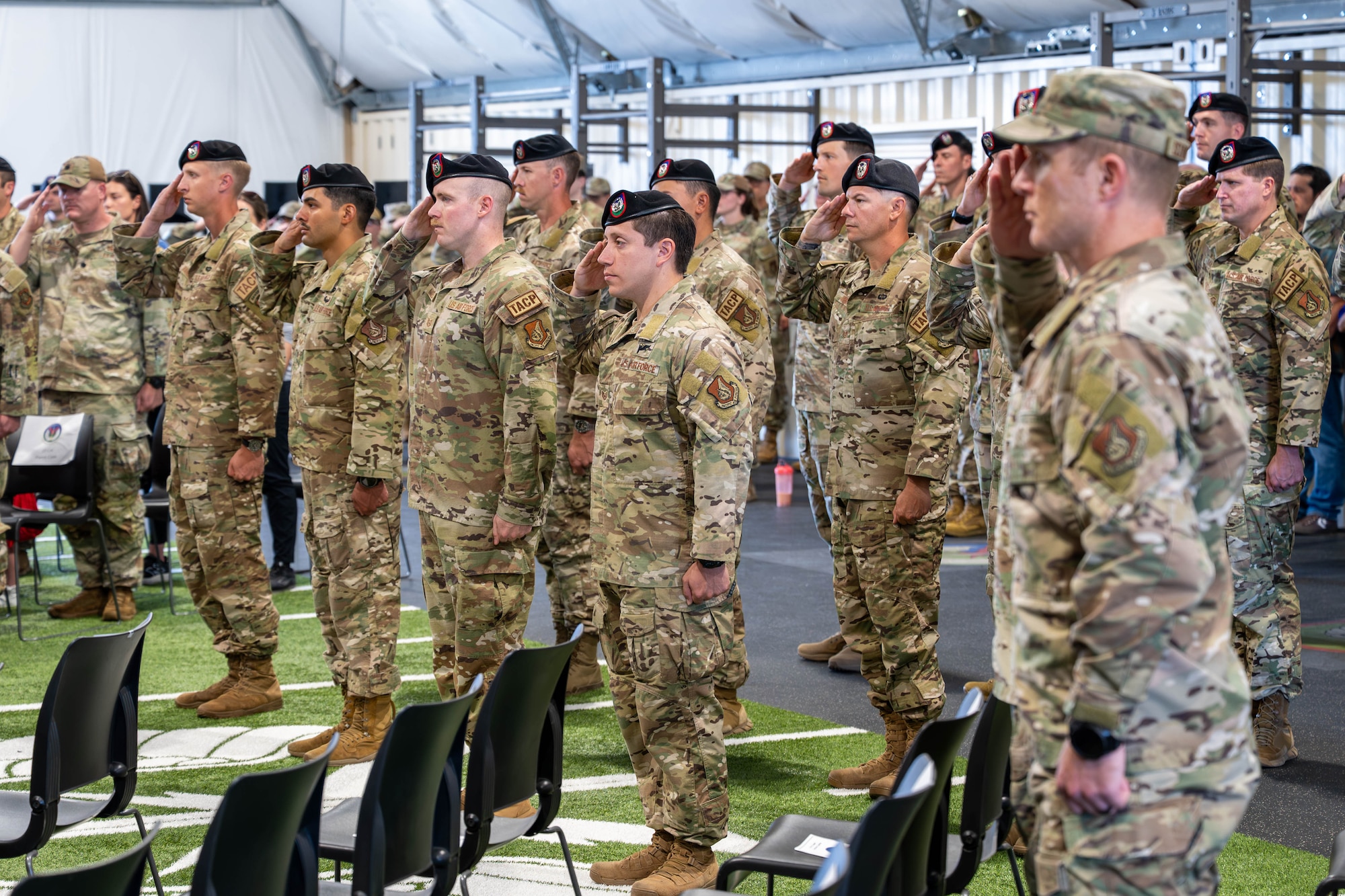 A room of men and women salute.