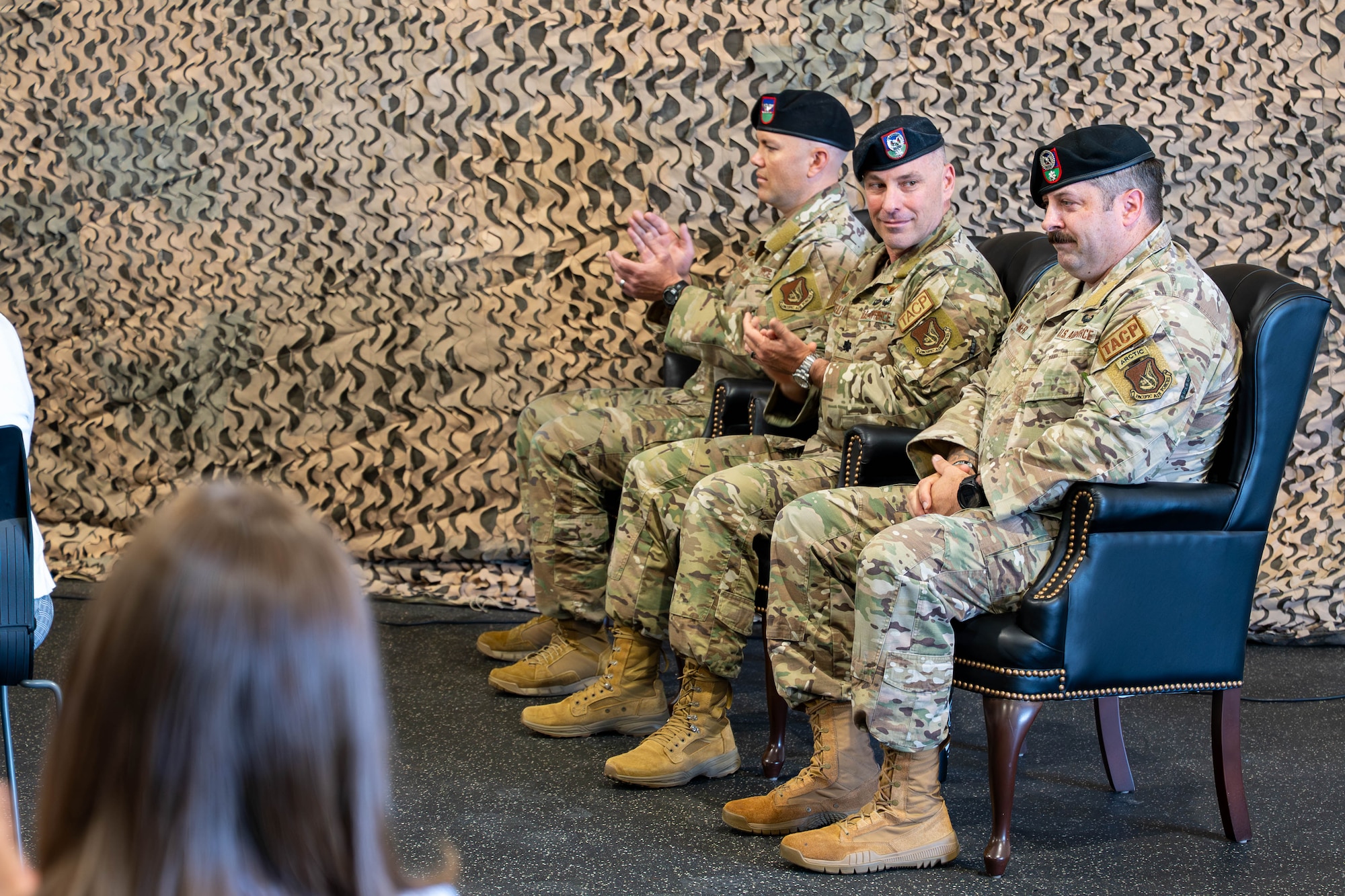 Three men sit next to each other in armchairs.