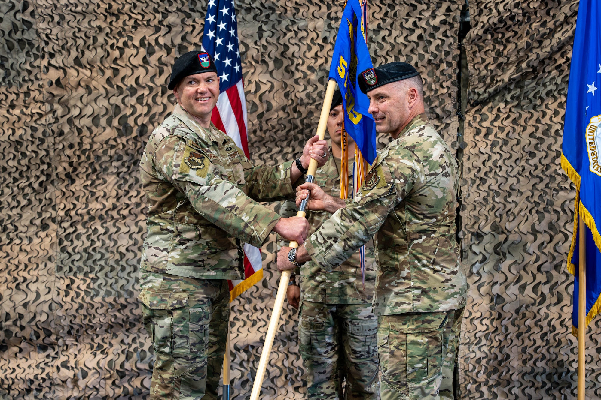 Two men stand holding a flag.
