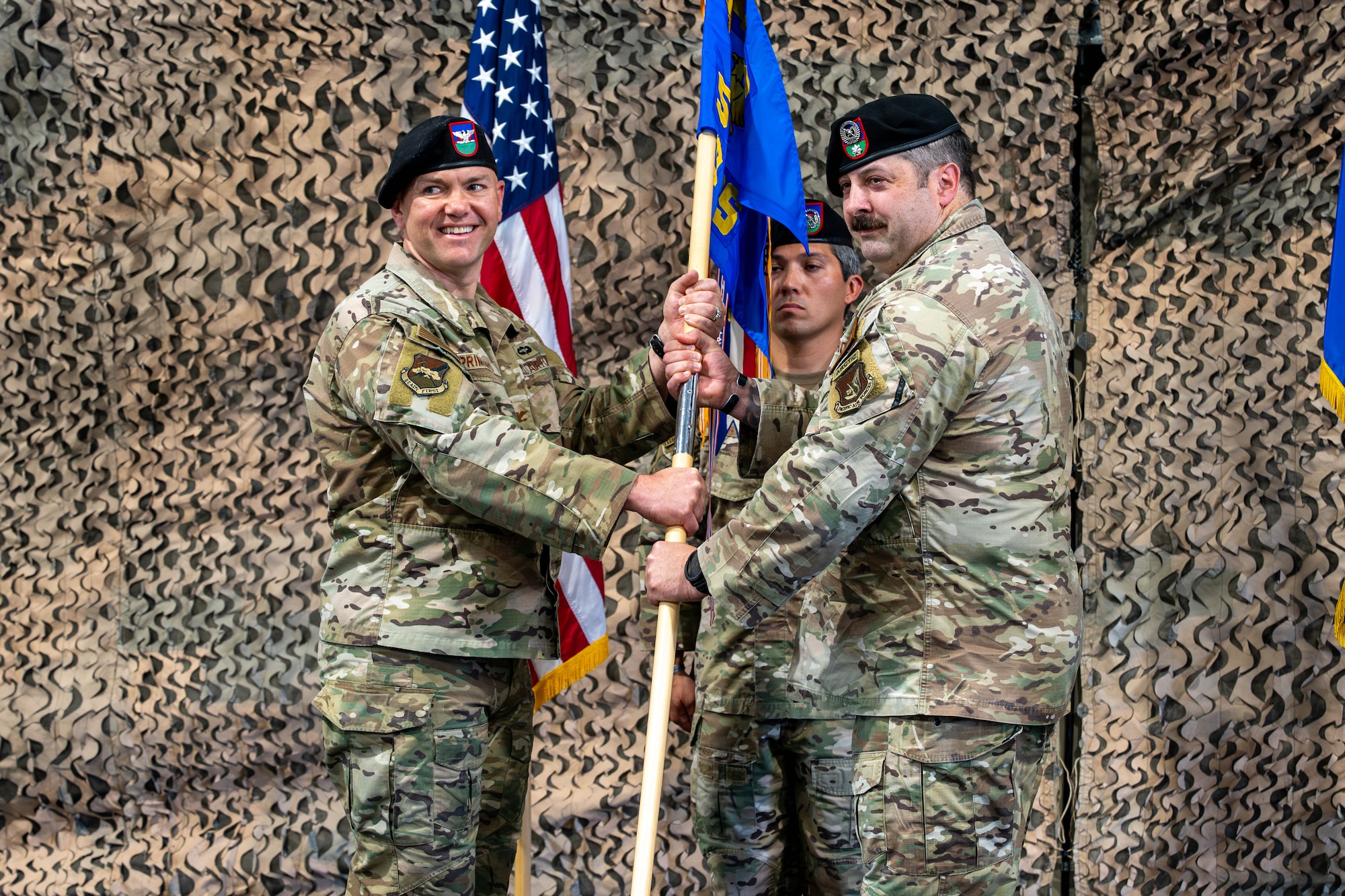 Two men stand holding a flag.