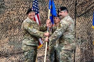 Two men stand holding a flag.