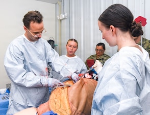Lieutenant Commander Justin Frisenda, left, assigned to Expeditionary Medical Facility Kilo, sutures a simulated  abdominal casualty during a training at the NMCCL Healthcare Simulation and Bioskills Center, on June 23, 2026. EMF-Kilo is the expeditionary readiness platform attached to Navy Medicine Readiness and Training Command Camp Lejeune and is comprised of approximately hundreds of personnel ready to deploy field hospital capabilities during humanitarian or combat mission. (U.S. Navy photo by Mass Communications Specialist 2nd Class Justin Woods)
