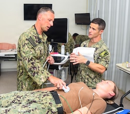 Lieutenant Commander Michael Feroli, left, assigned to Expeditionary Medical Facility Kilo, performs an abdominal ultrasound on a simulated casualty during a training at the NMCCL Healthcare Simulation and Bioskills Center, on June 23, 2026. EMF-Kilo is the expeditionary readiness platform attached to Navy Medicine Readiness and Training Command Camp Lejeune and is comprised of approximately hundreds of personnel ready to deploy field hospital capabilities during humanitarian or combat mission. (U.S. Navy photo by Mass Communications Specialist 2nd Class Justin Woods)
