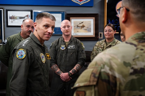 A U.S. Navy Admiral speaks with a large group of U.S. Air Force Airmen.