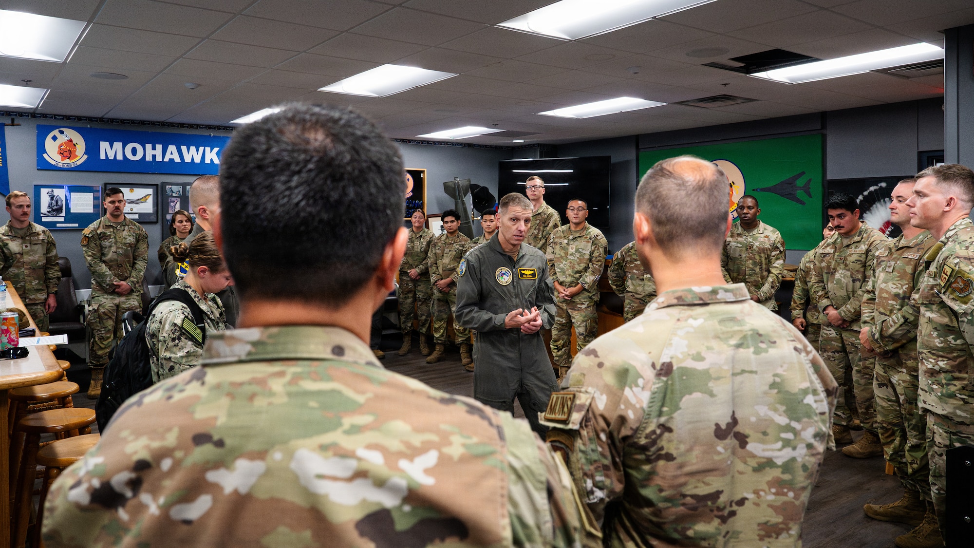 A U.S. Navy Admiral speaks with a large group of U.S. Air Force Airmen.