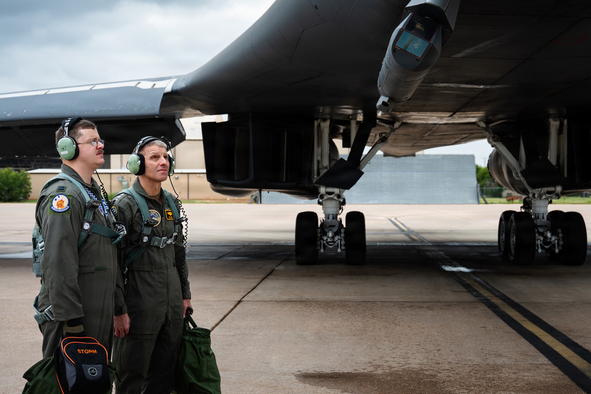 A U.S. Navy Admiral and a U.S. Air Force pilot look at a B-1B Lancer on the flightline.