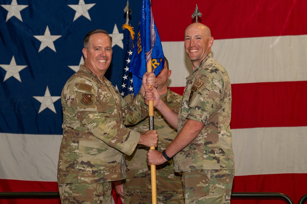 U.S. Air Force Col. Timothy Foster, 354th Mission Support Group commander, left, passes a guidon to Lt. Col. Peter Daigle, right, 354th Logistics Readiness Squadron outgoing commander, during a change of command ceremony at Eielson Air Force Base, Alaska, June 18, 2026.