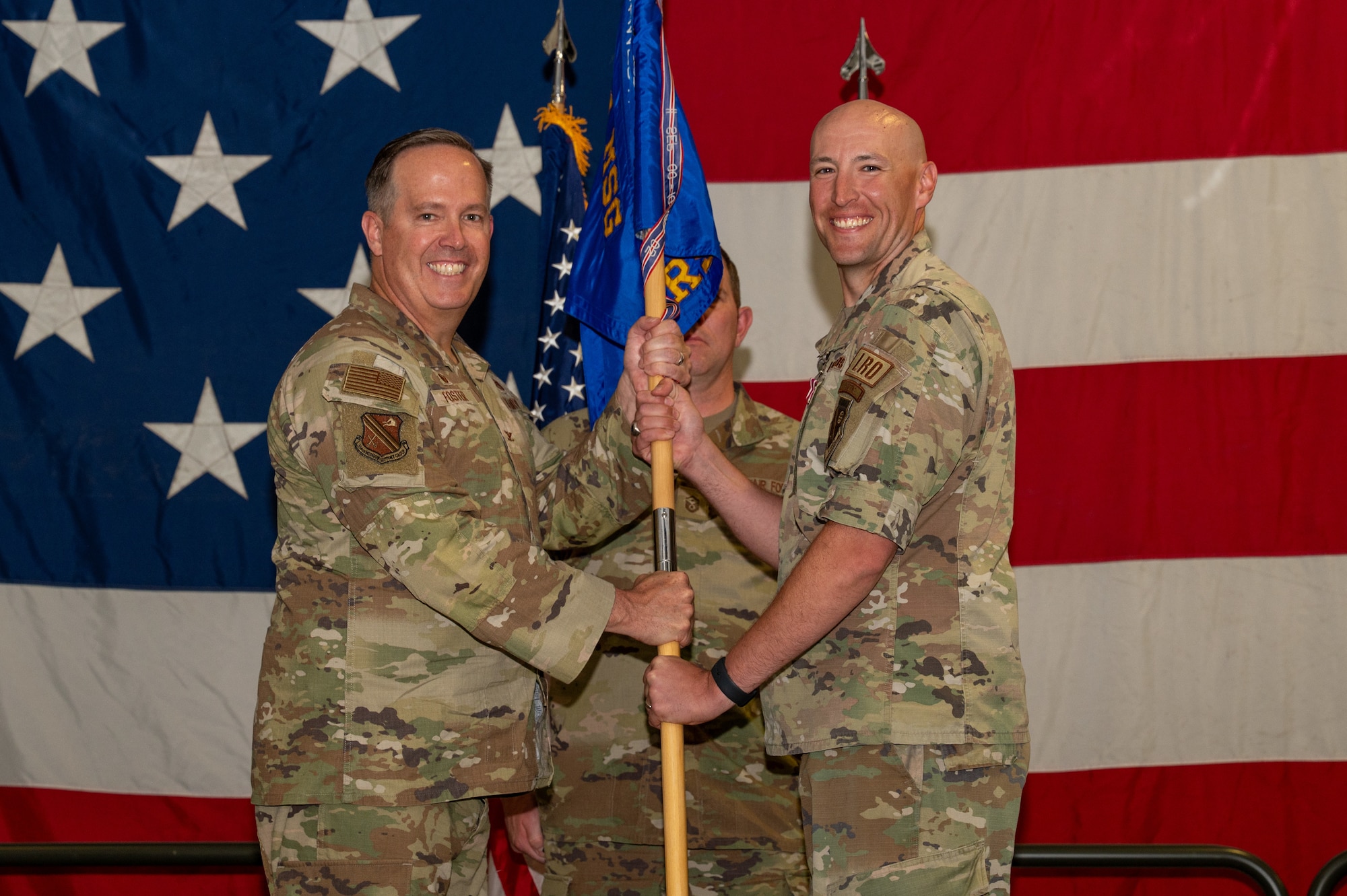 U.S. Air Force Col. Timothy Foster, 354th Mission Support Group commander, left, passes a guidon to Lt. Col. Peter Daigle, right, 354th Logistics Readiness Squadron outgoing commander, during a change of command ceremony at Eielson Air Force Base, Alaska, June 18, 2026.