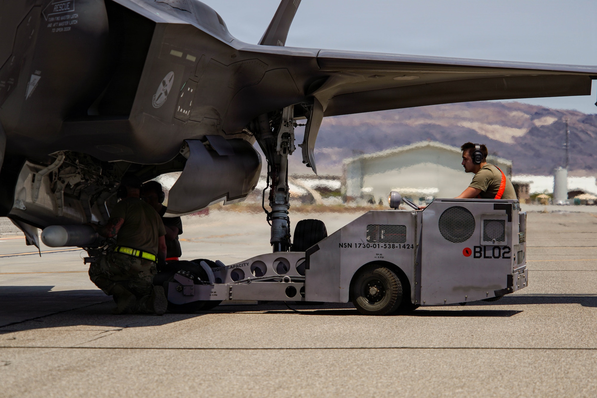 Three U.S. Air Force weapons load crew members assigned to the 57th Maintenance Group load an inert air-to-air missile onto an F-35A Lightning II during exercise VENOM FORGE at Creech Air Force Base, Nevada, June 17, 2026. Creech AFB provided the majority of support equipment required for the exercises' execution, facilitated access across the installation and helped integrate aircraft and operations separate from typical day-to-day mission requirements. (U.S. Air Force photo by Staff Sgt. Jake Jacobsen)