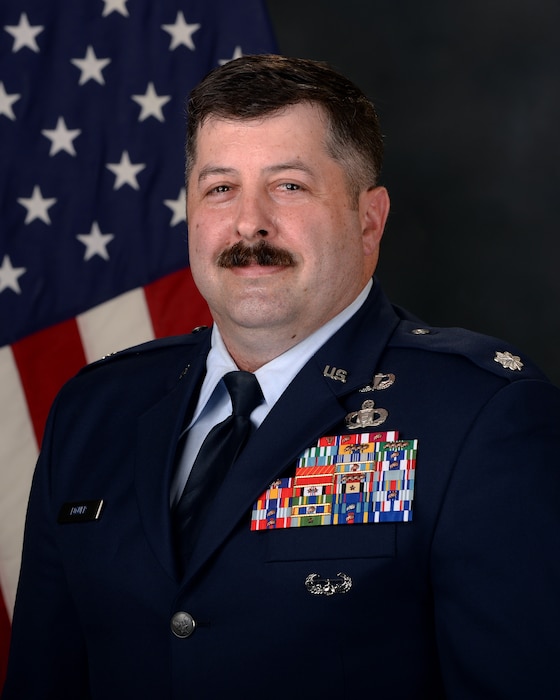 A man sits in front of a U.S. flag.