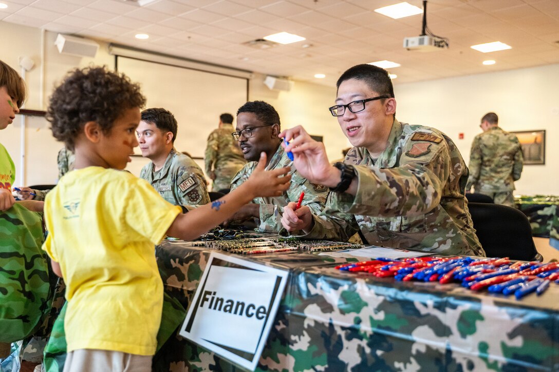 U.S. Air Force Airman 1st Class Li Runzhung, a financial operation technician to the 316th Wing , hands out pens to children