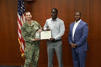 Naval Surface Warfare Center, Philadelphia Division (NSWCPD) Commanding Officer Capt. Ashley Wright and Technical Director Nigel C. Thijs, SES, present Electrical Engineer Maboury Gueye with the Department of the Navy Civilian Service Commendation Medal during NSWCPD’s Fiscal Year 2026 Third Quarter Awards Ceremony held June 17, 2026. Gueye was recognized for superior performance while serving as a subject matter expert providing urgent Support Equipment and Aircraft Launch and Recovery Equipment fleet support in a critical, forward-deployed environment. (U.S. Navy photo by Jay Butterbaugh, CTR)