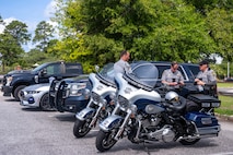 A photo of three police officers standing alongside their collection of patrol vehicles.