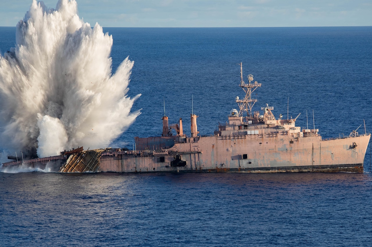 Water shoots in the air after a torpedo hits a ship in the ocean.