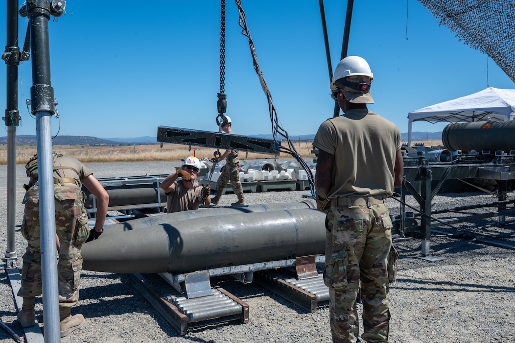 U.S. Air Force Airmen assigned to the Air Force Combat Ammunition Center Class 26-006 work together to lift a bomb during a fragmentation order preparation exercise at Beale Air Force Base, California, June 11, 2026.
