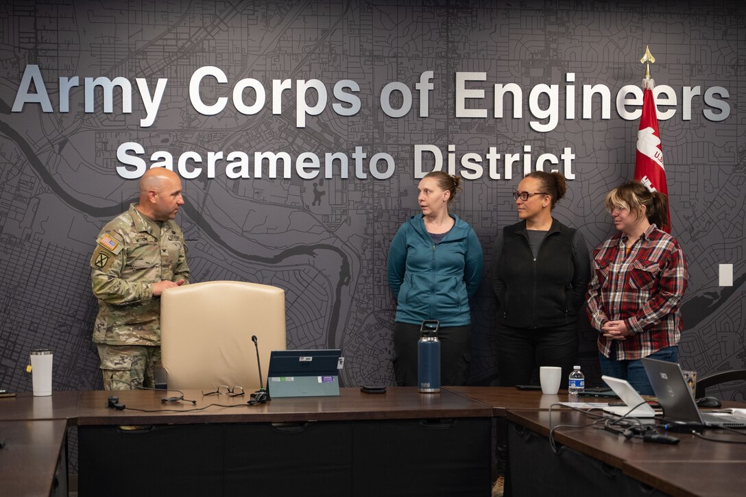 Sacramento District Commander Col. Robert McTighe (left) presents a commander's coin to (from left) Shelley McCoy, Jerilynn Hilmar and Elizabeth "Ellie" Hayes Dec. 8, 2025, at Sacramento District headquarters. The three employees were recognized for their quick response to a medical emergency, drawing on their training and past experiences to assist a distressed colleague and help facilitate the medical attention she needed