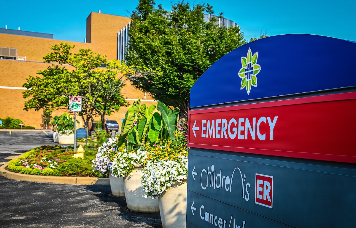 Blue sign and red sign. Emergency in white with red background pointing in the direction of the emergency department.
