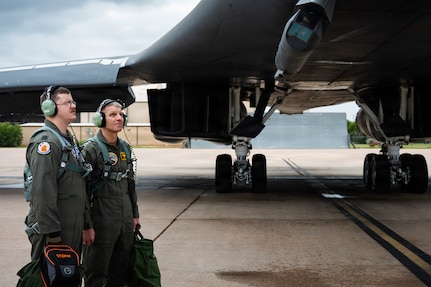 A U.S. Navy Admiral and a U.S. Air Force pilot look at a B-1B Lancer on the flightline.