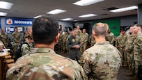 A U.S. Navy Admiral speaks with a large group of U.S. Air Force Airmen.