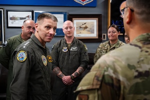 A U.S. Navy Admiral speaks with a large group of U.S. Air Force Airmen.