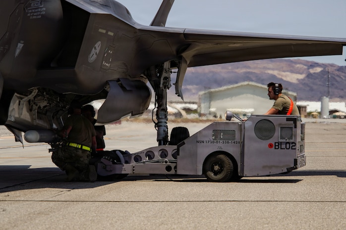 Three U.S. Air Force weapons load crew members assigned to the 57th Maintenance Group load an inert air-to-air missile onto an F-35A Lightning II during exercise VENOM FORGE at Creech Air Force Base, Nevada, June 17, 2026. Creech AFB provided the majority of support equipment required for the exercises' execution, facilitated access across the installation and helped integrate aircraft and operations separate from typical day-to-day mission requirements. (U.S. Air Force photo by Staff Sgt. Jake Jacobsen)