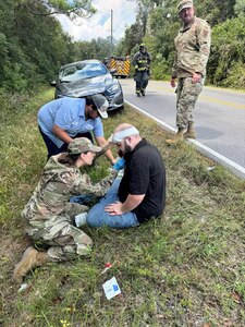 Montana Air Guard Capt. Caitlyn Cayer, who is also a nurse practitioner, administers aid to a man involved in a traffic wreck in Gulfport, Miss., Sept. 22, 2025. Master Sgt. Kraig Kimball, top right, helped pull the driver from a car fire and escorted him to safety seconds before the car engulfed in flames.