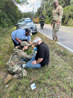 Montana Air Guard Capt. Caitlyn Cayer, who is also a nurse practitioner, administers aid to a man involved in a traffic wreck in Gulfport, Miss., Sept. 22, 2025. Master Sgt. Kraig Kimball, top right, helped pull the driver from a car fire and escorted him to safety seconds before the car engulfed in flames.