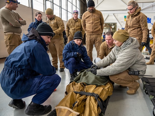 U.S. Coast Guard medical professionals transfer the care of a patient to U.S. Navy Sailors assigned to Expeditionary Resuscitative Surgical System (ERSS) Team 3 during a ship-to-shore medical evacuation exercise as part of ARCTIC EDGE 2026 (AE26) in Kodiak, Alaska, Feb. 26, 2026. AE26 is a NORAD and U.S. Northern Command-led homeland defense exercise designed to improve readiness, demonstrate capabilities, and enhance Joint and Allied Force interoperability in the Arctic. (U.S. Navy photo by Mass Communication Specialist 1st Class Abigayle Lutz)