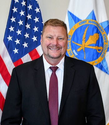 Photo of a man in front of the American and AMSC flag.