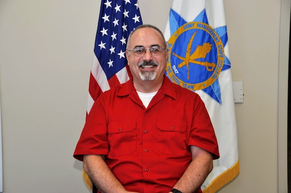 Photo of a man in front of the American and AMSC flag.