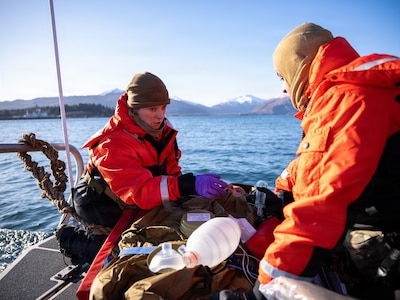 U.S. Navy Lt. Hannah Cunningham, left, assigned to En-route Care System (ERCS) Team 52, and U.S. Navy Hospital Corpsman 1st Class Daniel Rodriguez, right, assigned to ERCS Team 52, treat a patient aboard a small boat during a ship-to-shore medical evacuation exercise as part of ARCTIC EDGE 2026 (AE26) in Kodiak, Alaska, Feb. 26, 2026. AE26 is a NORAD and U.S. Northern Command-led homeland defense exercise designed to improve readiness, demonstrate capabilities, and enhance Joint and Allied Force interoperability in the Arctic. (U.S. Navy photo by Mass Communication Specialist 1st Class Abigayle Lutz)