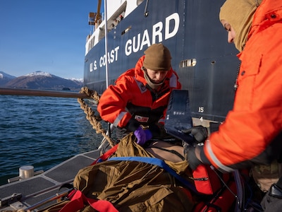 U.S. Navy Lt. Hannah Cunningham, left, assigned to En-route Care System (ERCS) Team 52, and U.S. Navy Hospital Corpsman 1st Class Daniel Rodriguez, assigned to ERCS Team 52, treat a patient aboard a Rigid Hull Inflatable Boat (RHIB) during a ship-to-shore medical evacuation exercise as part of ARCTIC EDGE 2026 (AE26) in Kodiak, Alaska, Feb. 26, 2026. AE26 is a NORAD and U.S. Northern Command-led homeland defense exercise designed to improve readiness, demonstrate capabilities, and enhance Joint and Allied Force interoperability in the Arctic. (U.S. Navy photo by Mass Communication Specialist 1st Class Abigayle Lutz)