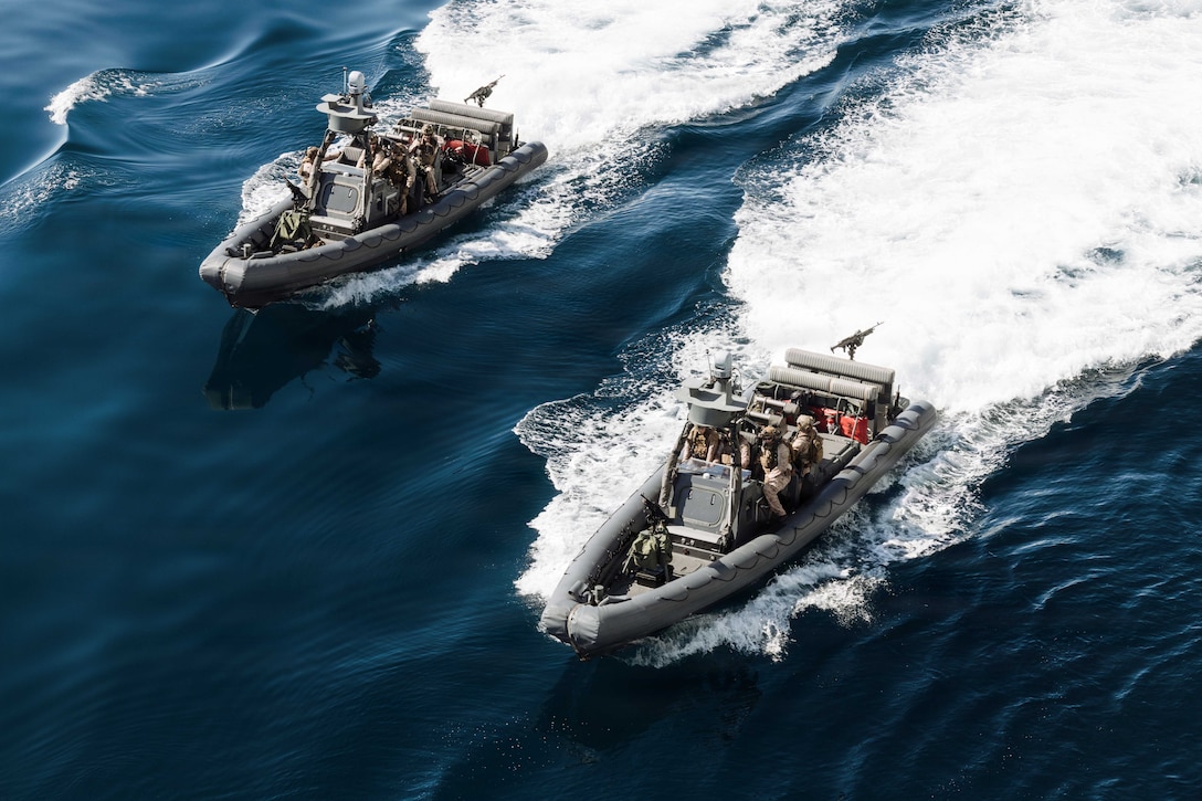Marines in tactical gear operate two rigid-hull inflatable boats as seen from above.