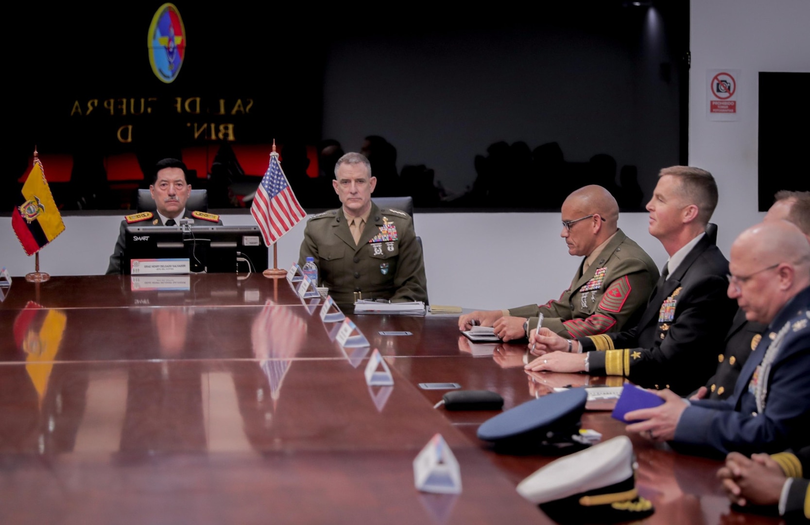 Senior officials in military uniforms and suits sit at a table.