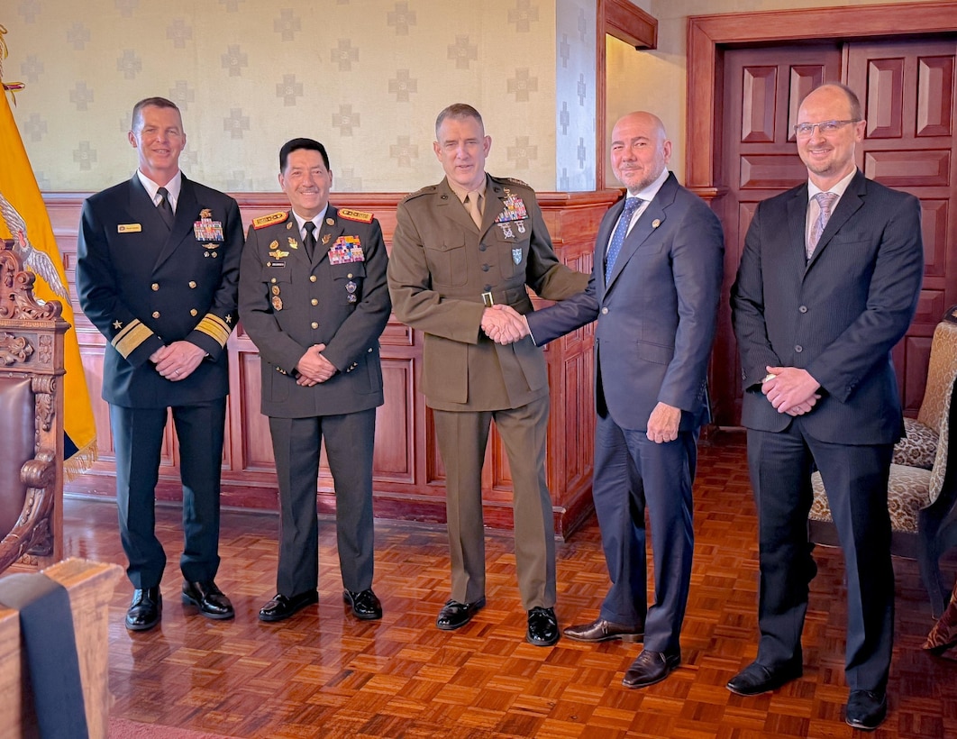 Senior officials in military uniforms and suits stand in a line for a group photo.