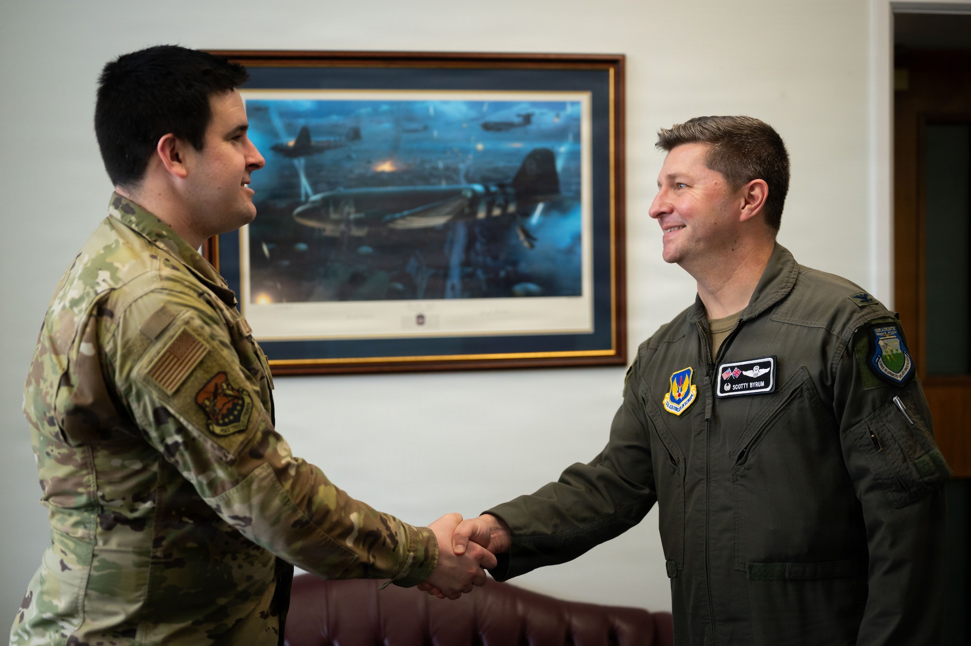 Two men in military uniforms shake hands. 