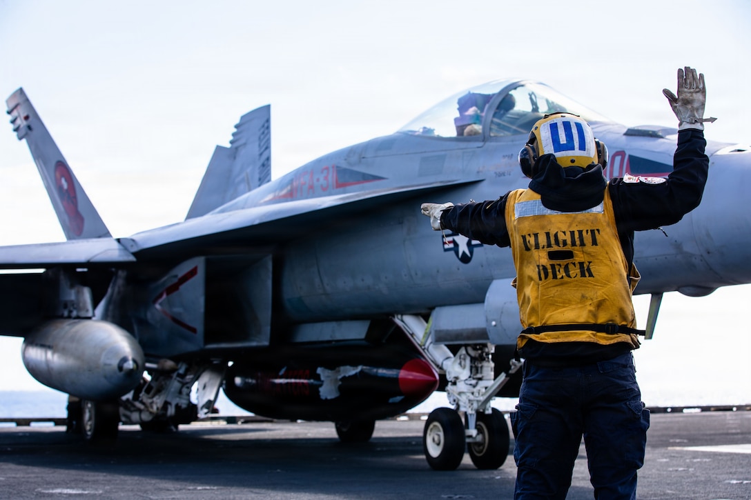 A U.S. Sailor signals to an F/A-18E Super Hornet aircraft, attached to Strike Fighter Squadron 31, on the flight deck of the world's largest aircraft carrier, USS Gerald R. Ford (CVN 78), while operating in support of Operation Epic Fury in the Eastern Mediterranean Sea, March 2, 2026. (U.S. Navy photo)