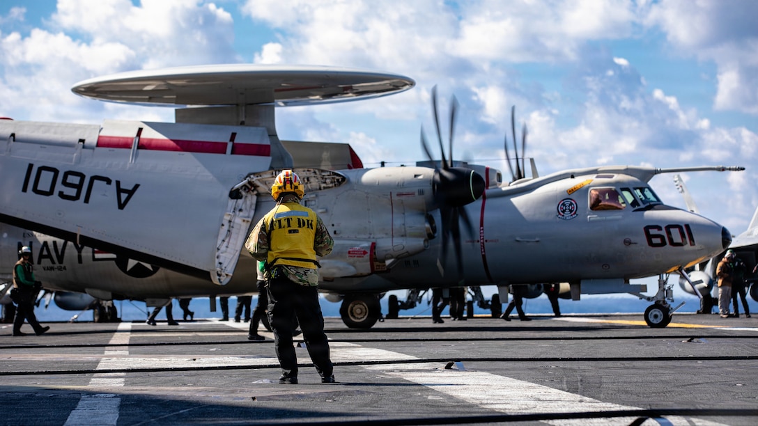A U.S. Sailor observes an E-2D Hawkeye, attached to Airborne Command and Control Squadron 124, taxi on the flight deck of the world’s largest aircraft carrier, USS Gerald R. Ford (CVN 78), while operating in support of Operation Epic Fury in the Eastern Mediterranean Sea, March 2, 2026. (U.S. Navy photo)