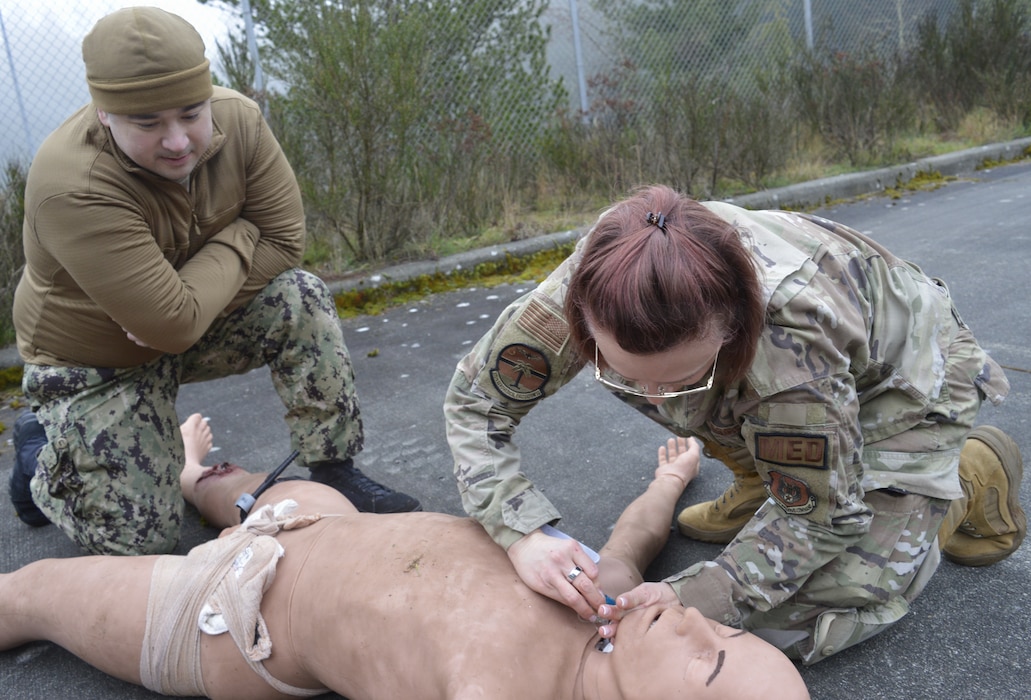 Hands on airway management… Under the watchful gaze of Navy Medicine Readiness Training Command Bremerton Tactical Combat Casualty Care instructors, 315th Aeromedical Evacuation Squadron personnel hone their medical response skills in treating traumatic injuries on the field of battle. The visiting Air Force personnel from Charleston Air Force Base, South Carolina, received intensive didactic module training before undergoing and completing their educational effort with actual hands-on application in the field. Amidst a mock firefight exploding around them, faux patient screams and bellowing demands from instructors, the 315th team were tested on conducting – with timely urgency - primary and secondary assessments, casualty movement, airway management, hemorrhage control, chest needle decompression, applying splinting and pressure dressings, and more (Official Navy photo by Douglas H Stutz, NHB/NMRTC Bremerton public affairs officer).