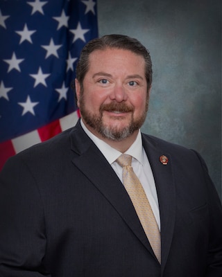 Man in suit in front of flag