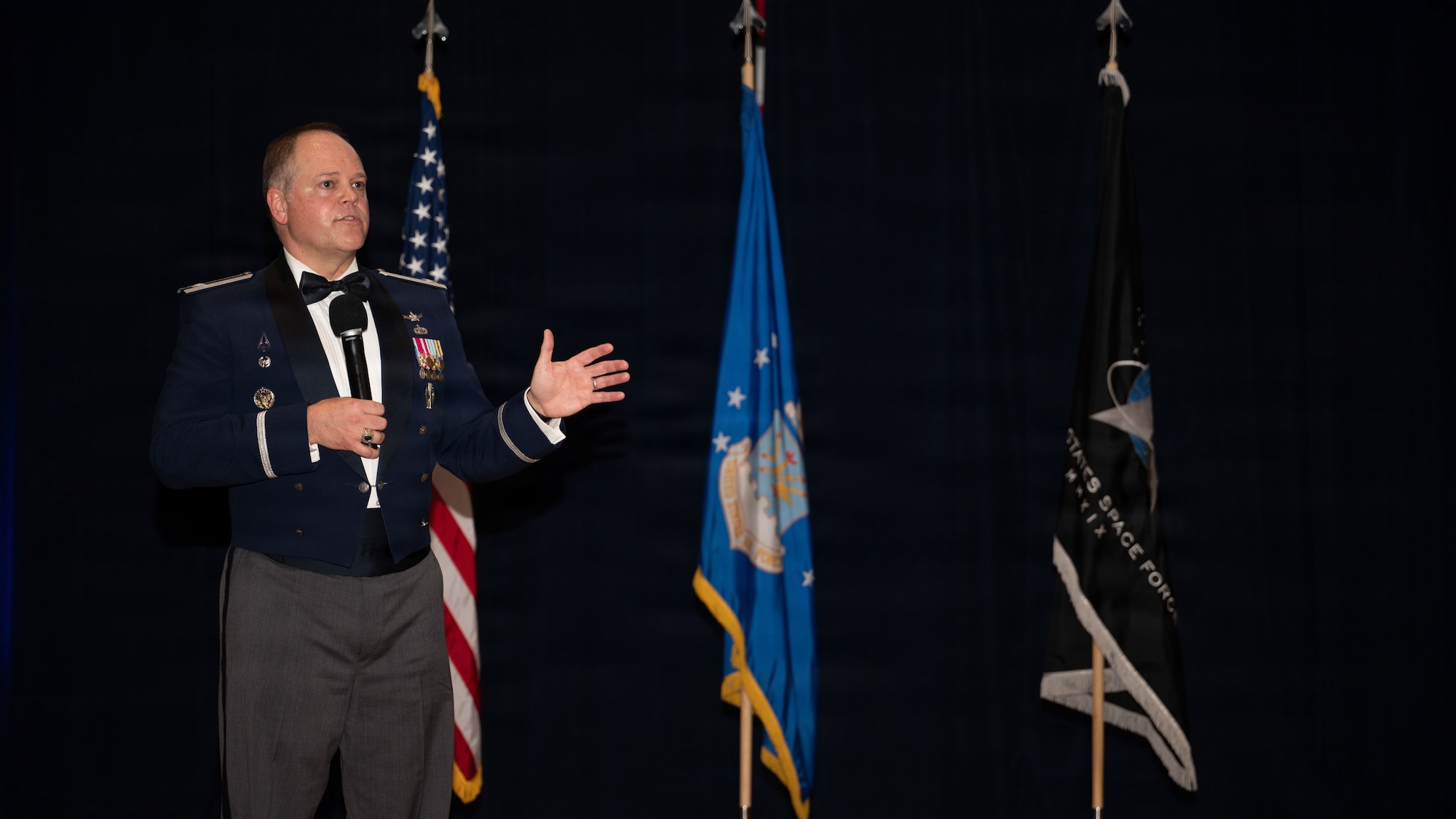 a person stand on a stage and speaks to a crowd