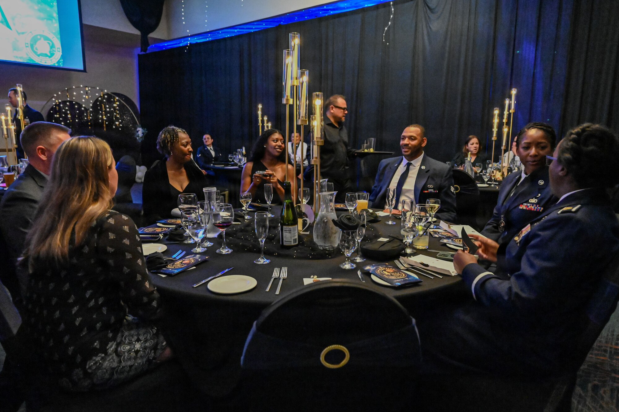 a group of people sit at a round dinner table
