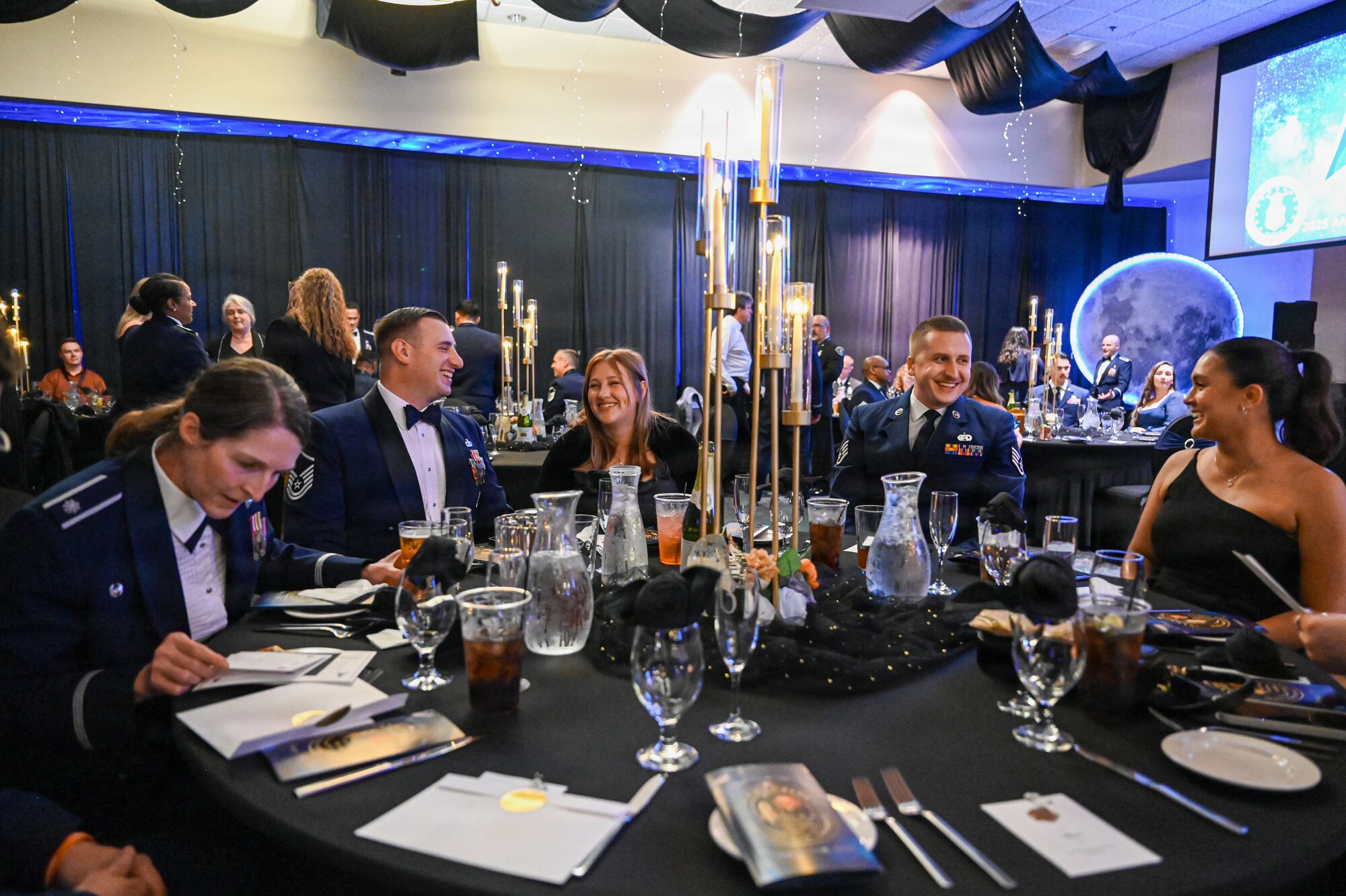 a group of people sit at a round dinner table