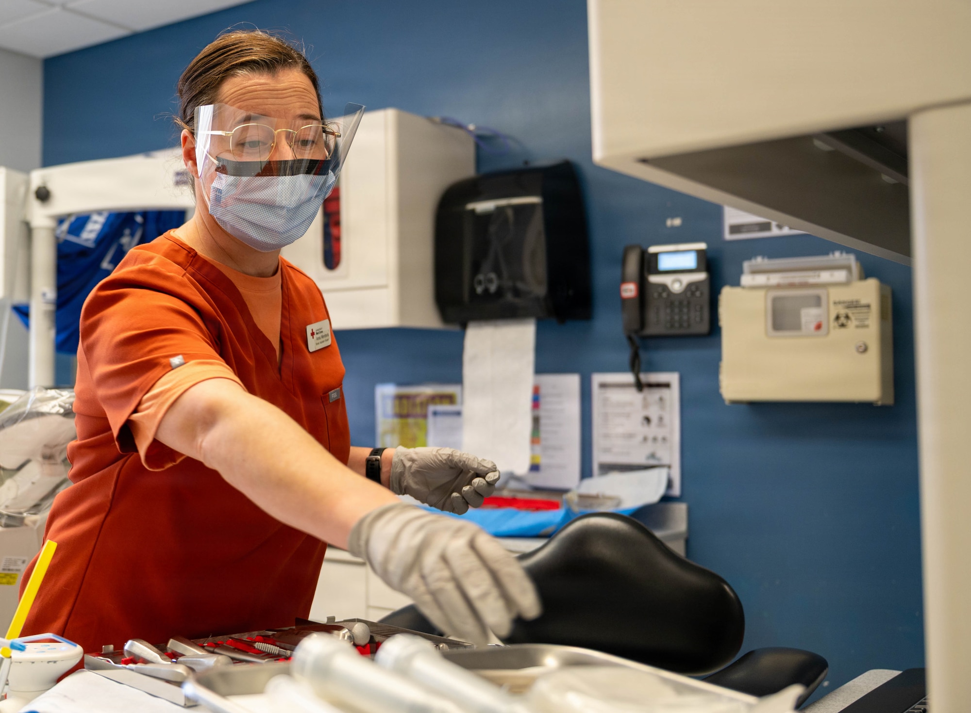 Dental assistant student reaches for dental equipment tool.